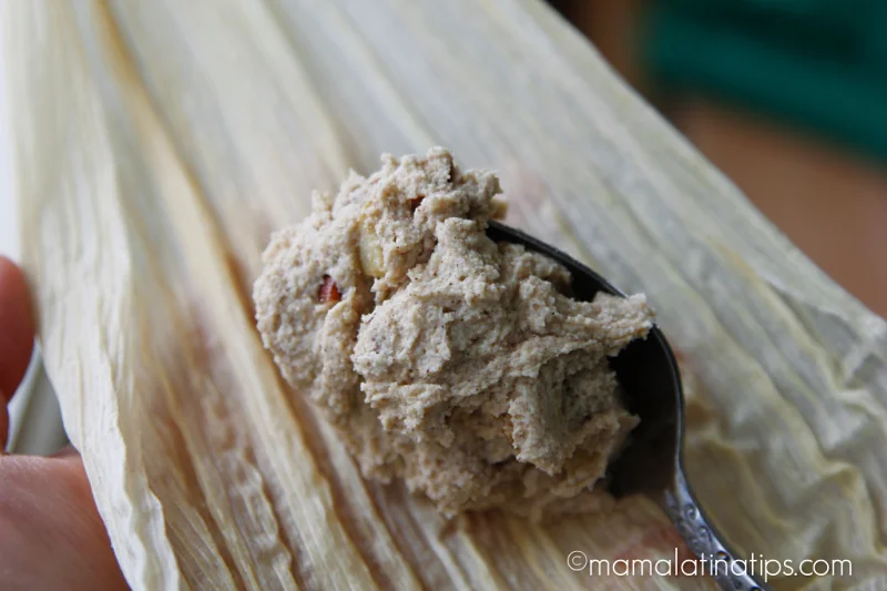 untando masa de tamal en la hoja de maíz