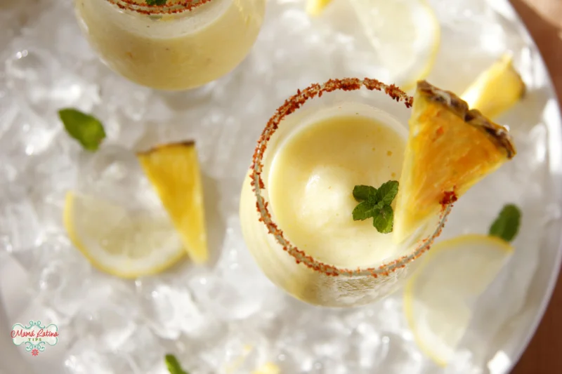 Margarita de piña congelada en un vaso adornado con piña y menta