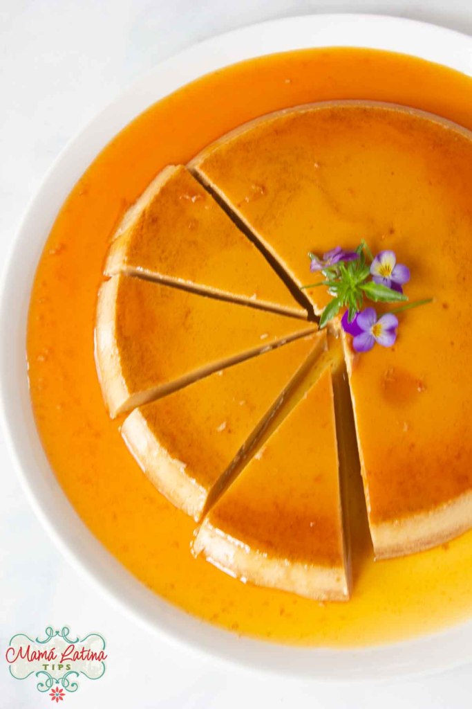A sliced coffee flan with a floral garnish, presented on a white plate with a caramel sauce.